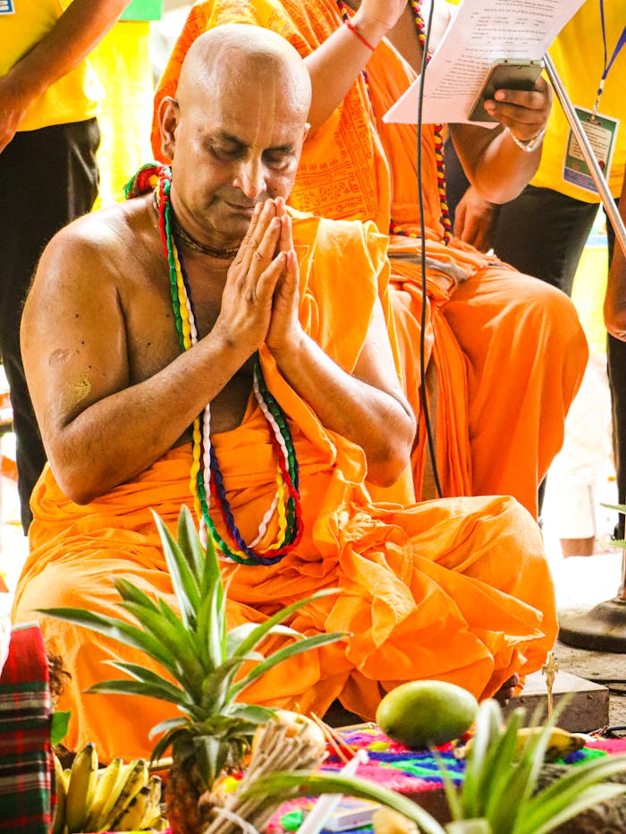 A Hindu monk performing a traditional ceremony with offerings in an outdoor setting.