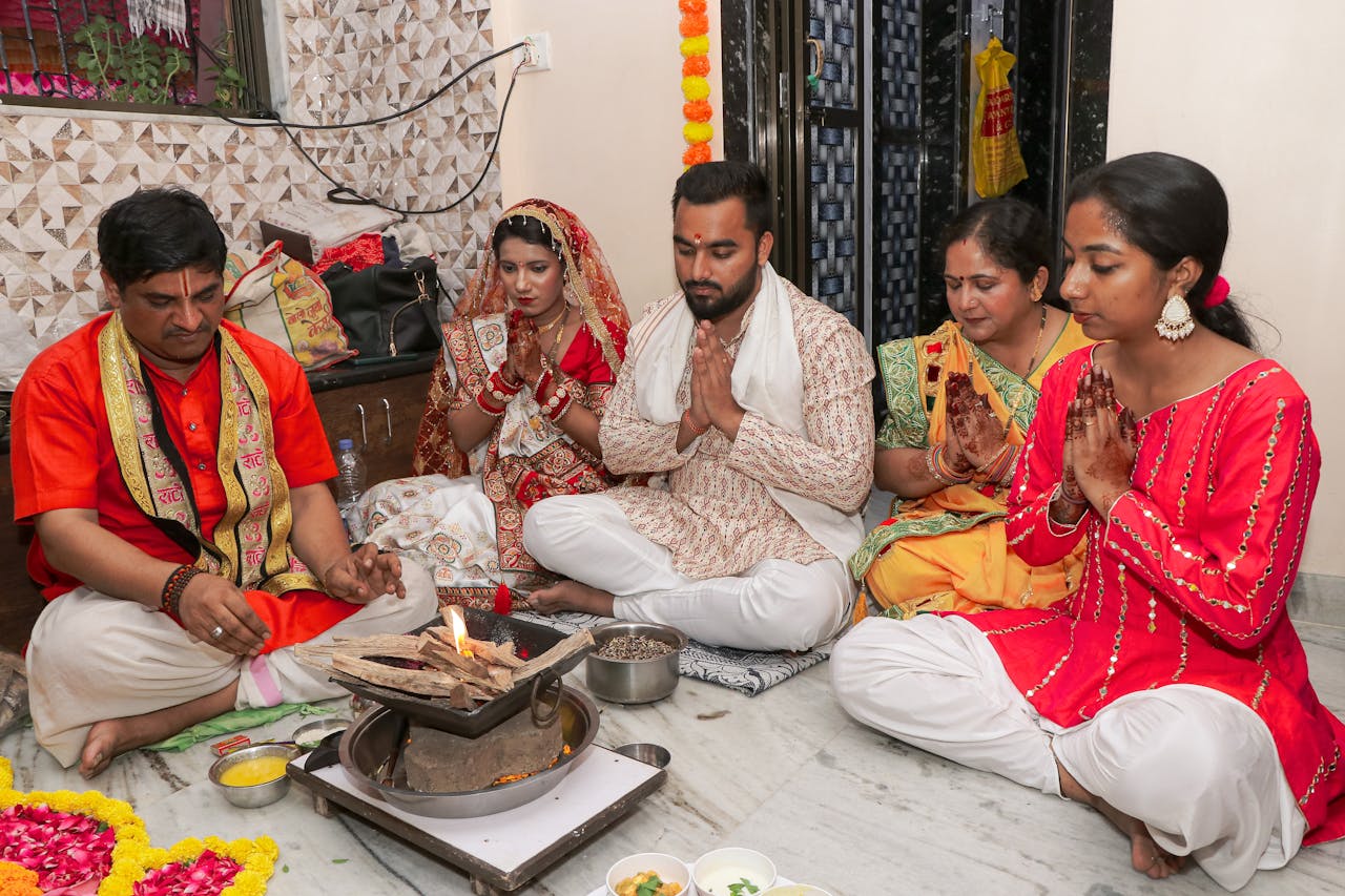 A group engaged in a traditional Indian wedding ritual with colorful attire and offerings.