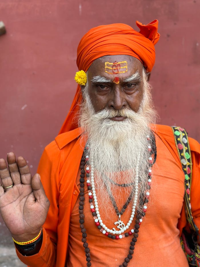 An Indian Sadhu in orange robes with ornate jewelry and face markings.